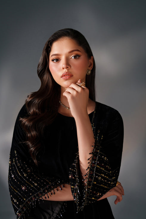 Woman wearing a black and gold outfit against a gray background