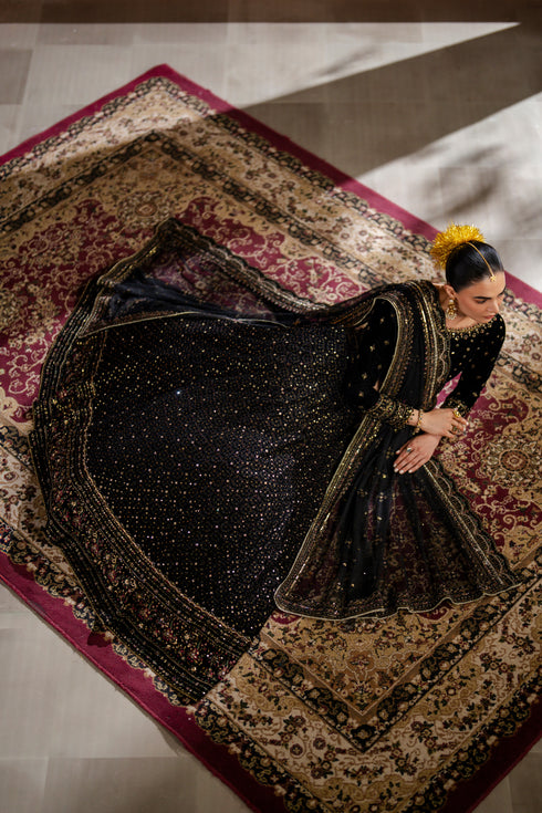Woman in a black and gold traditional outfit on a patterned rug