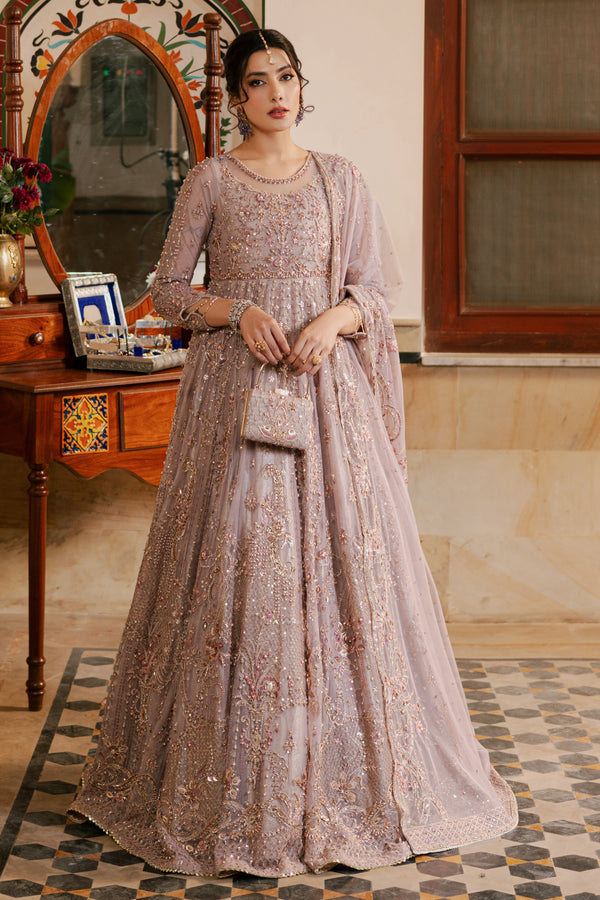 Model wearing full NAQSHI Nihan ensemble: heavily embellished dusty‑lilac net maxi frock, straight silk pants, embellished net dupatta & matching clutch