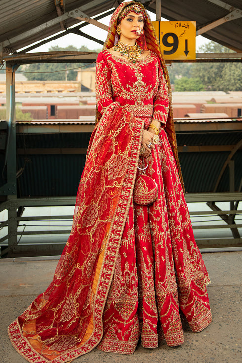 Naqshi Mastani carmine-red raw-silk lehenga choli showcasing all-over Mughal-inspired adda embroidery, cutwork borders, hanging tassels, styled with net and organza dupattas plus structured clutch.