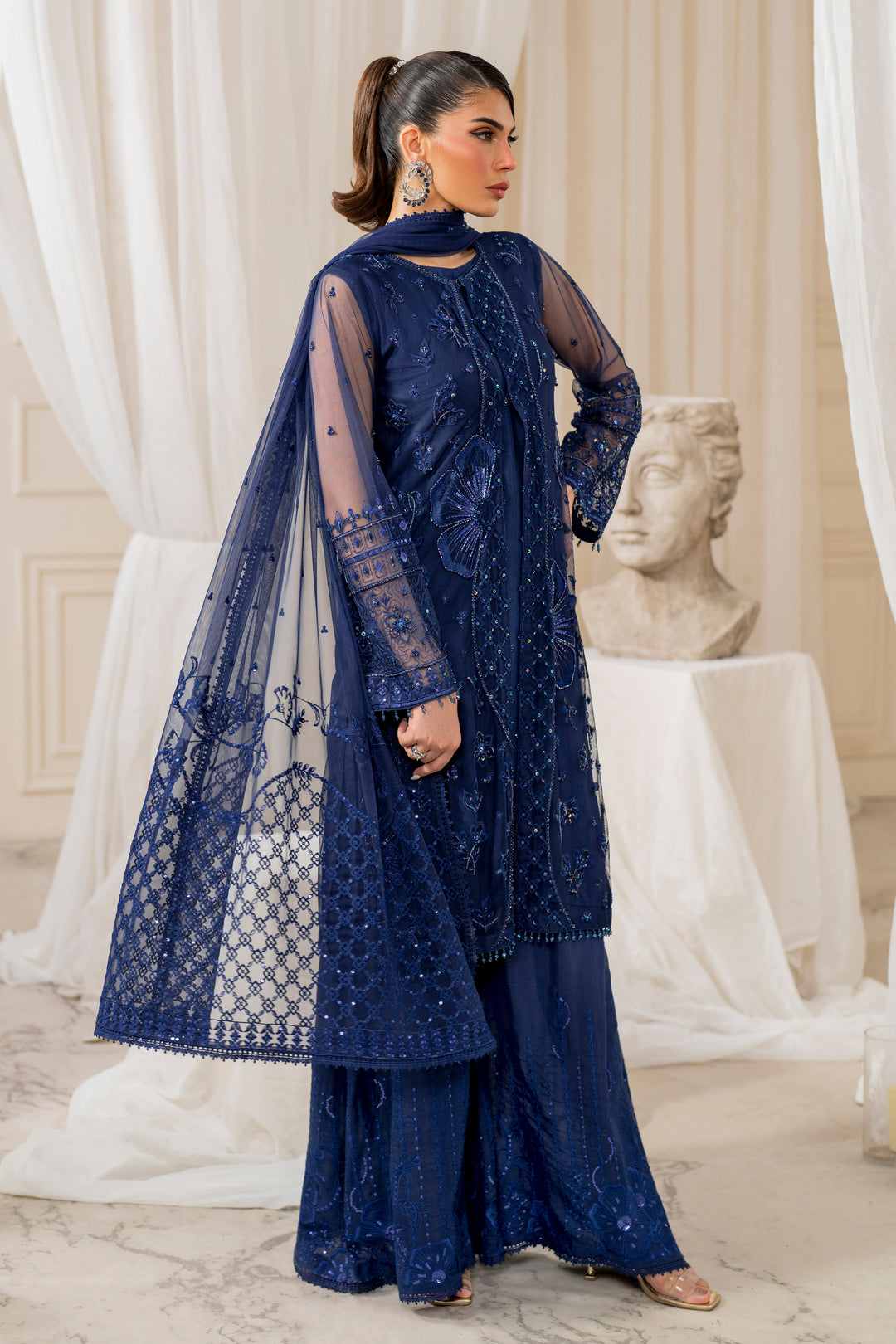 Side profile of naqshi nayal displaying flared cutline, bold flower embroidery, textured mid‑panel and flowing culottes for elegant evening wear.