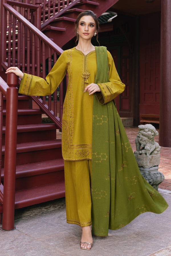 Woman in a green and mustard traditional outfit standing on a staircase.