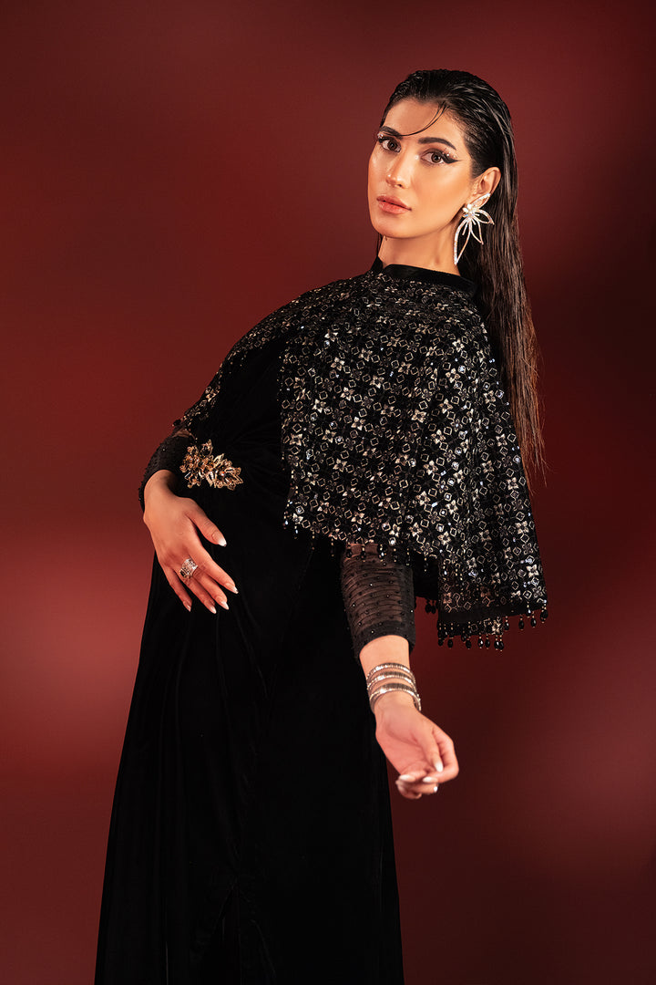 Three quarter pose of Ayna black formal dress showing fitted net sleeves and waist brooch detail, polished ready made dinner wear.