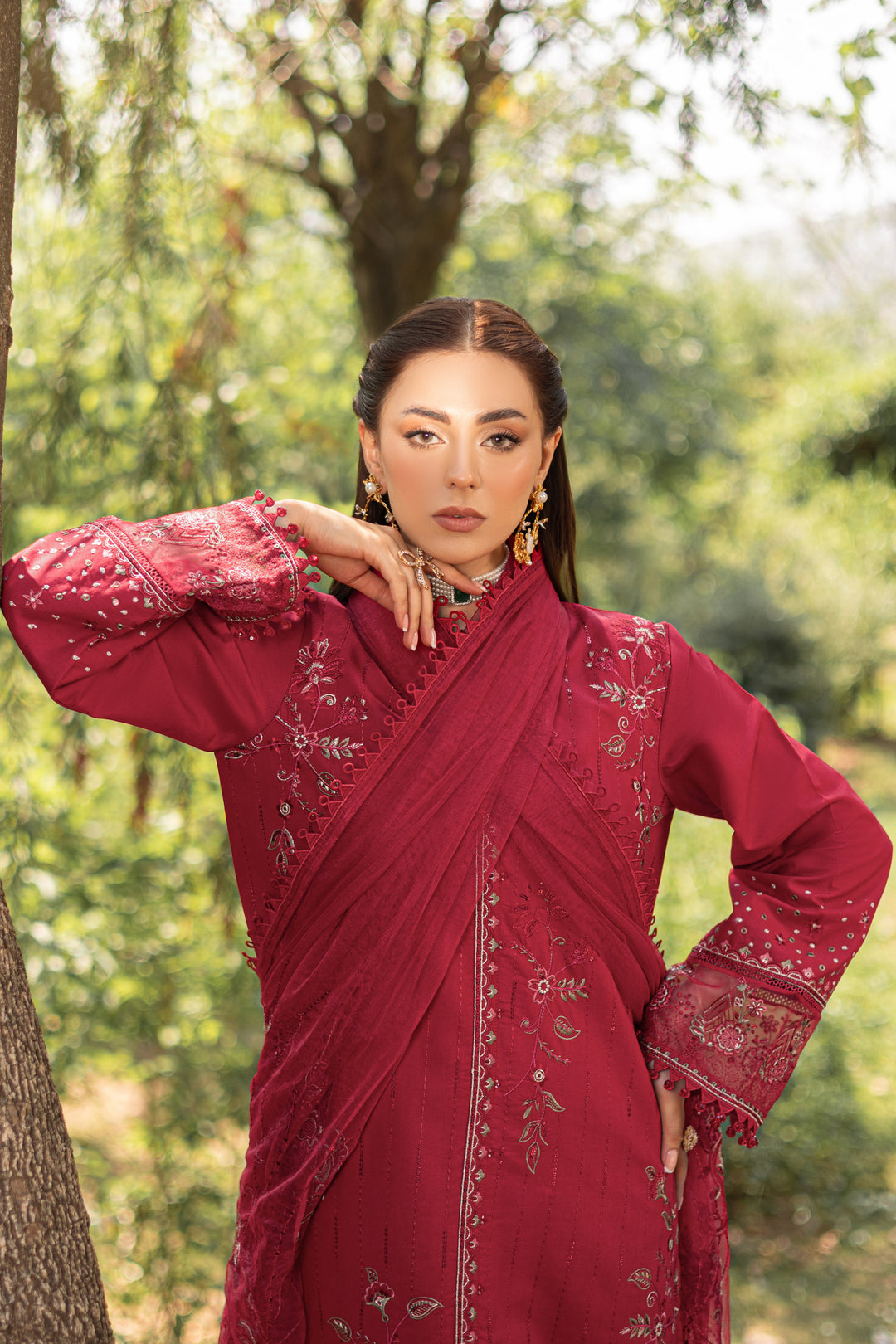 Three-quarter pose of NAQSHI garnet red outfit highlighting embroidered sleeves and detailed shirt fall