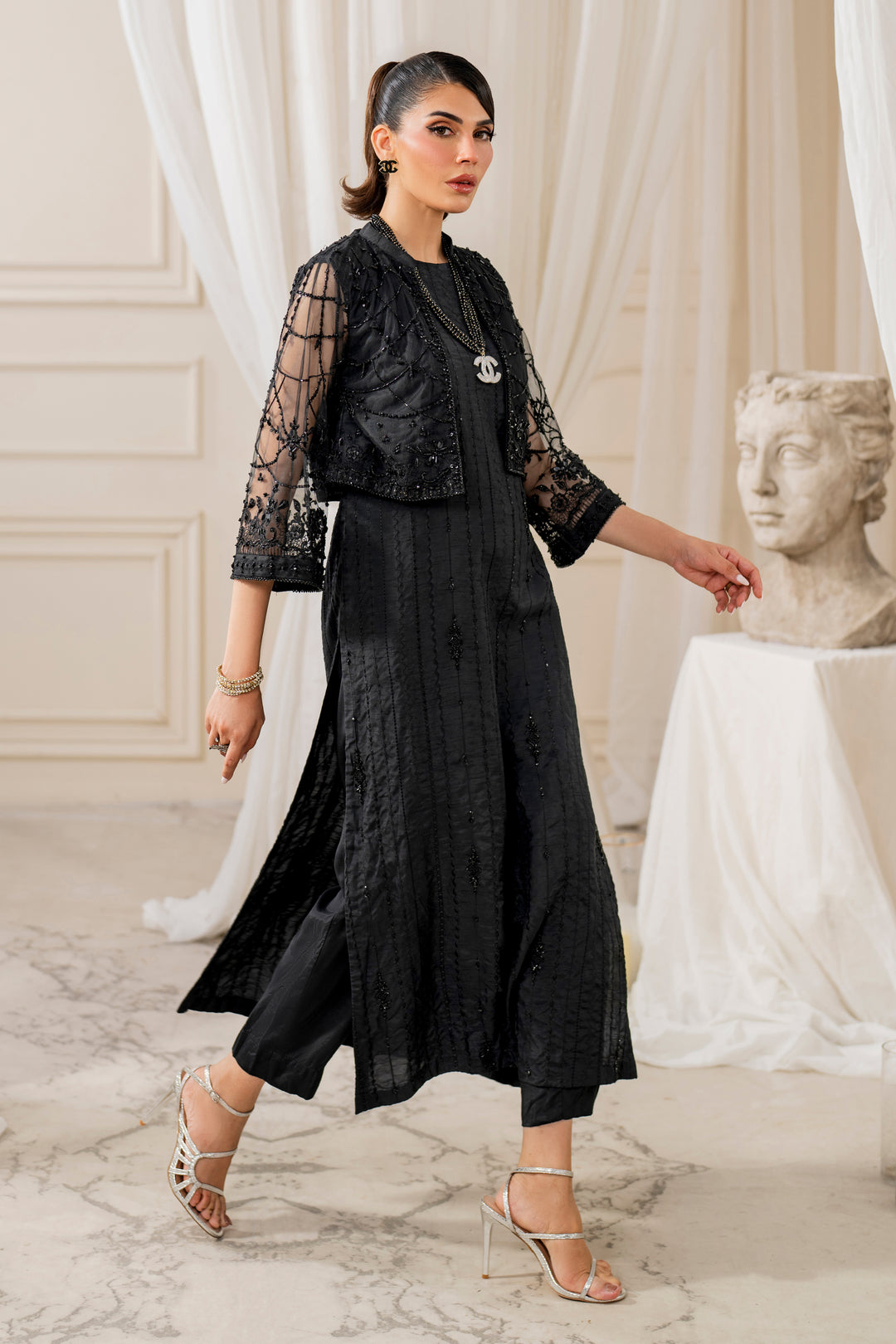Side view of Naqshi siara showcasing cropped net jacket sleeve embroidery, crystal‑bead edging and sleek straight raw‑silk shirt silhouette.

