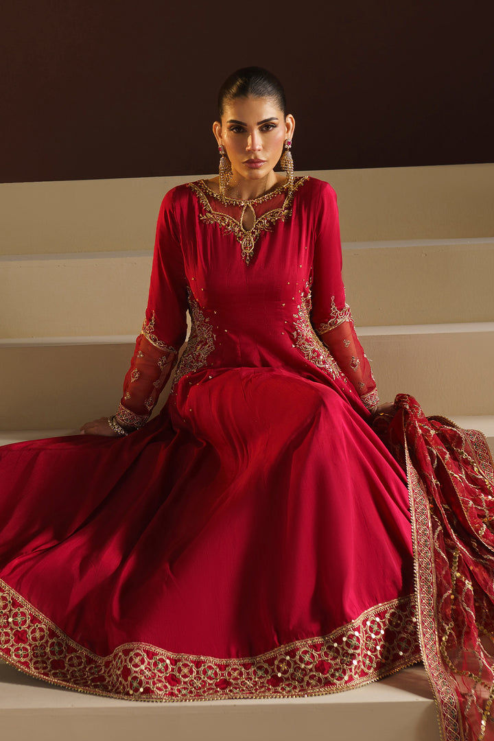 Front seated view of NAQSHI VANI red wedding wear frock highlighting heavy embroidered hem border