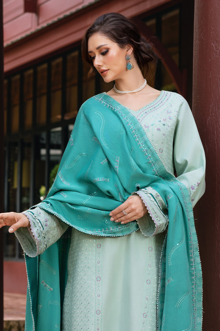 Woman wearing a teal and light green traditional outfit with a matching shawl.