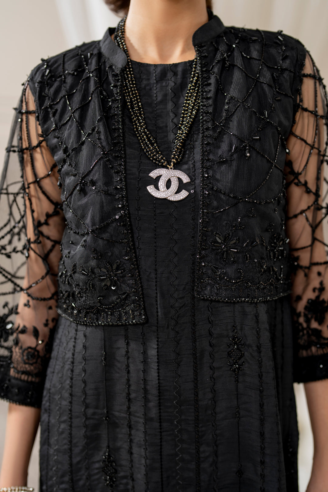 Close-up of naqshi siara cropped jacket sleeve cuff featuring dense net embroidery, crystals, beads &amp; hand‑made hangings.