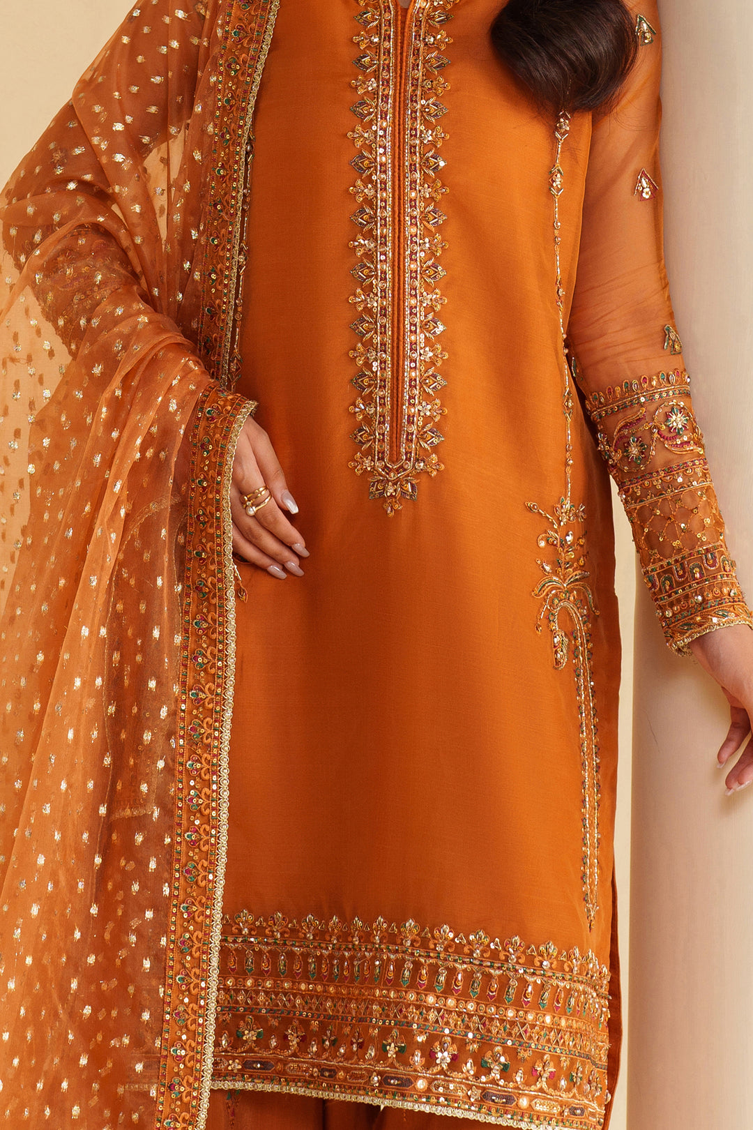 Close-up of NAQSHI burnt orange formal dress showing detailed embroidery on front and dupatta with premium stitched quality