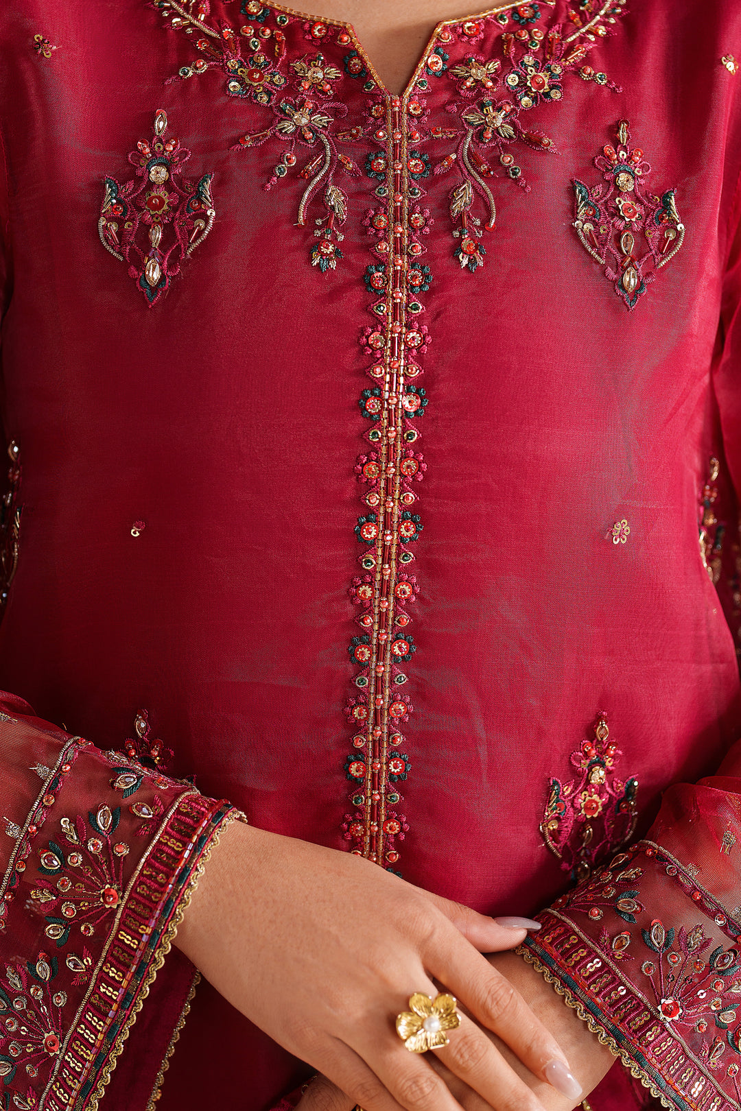 Close-up of NAQSHI deep red formal dress showing fine embroidery on neckline and front panel with premium finish