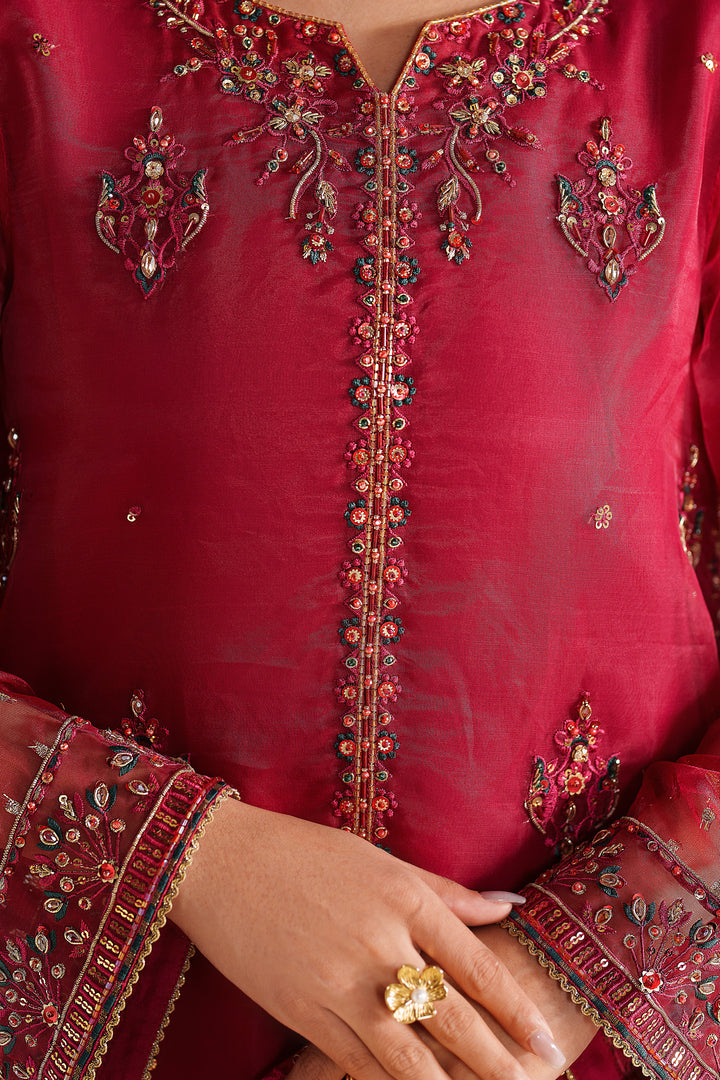 Close-up of NAQSHI deep red formal dress showing fine embroidery on neckline and front panel with premium finish