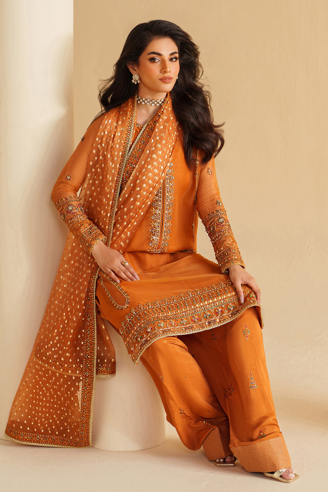NAQSHI burnt orange ready-to-wear formal outfit styled in seated pose, showing graceful fall and refined festive look