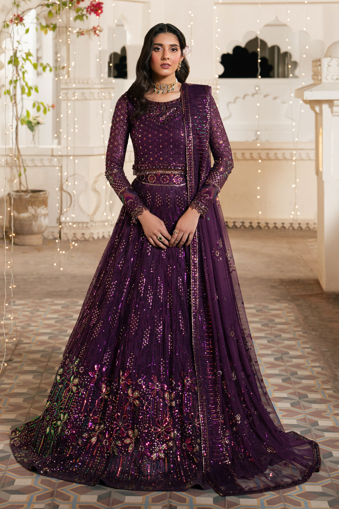 Woman wearing a purple embroidered traditional outfit in an indoor setting.