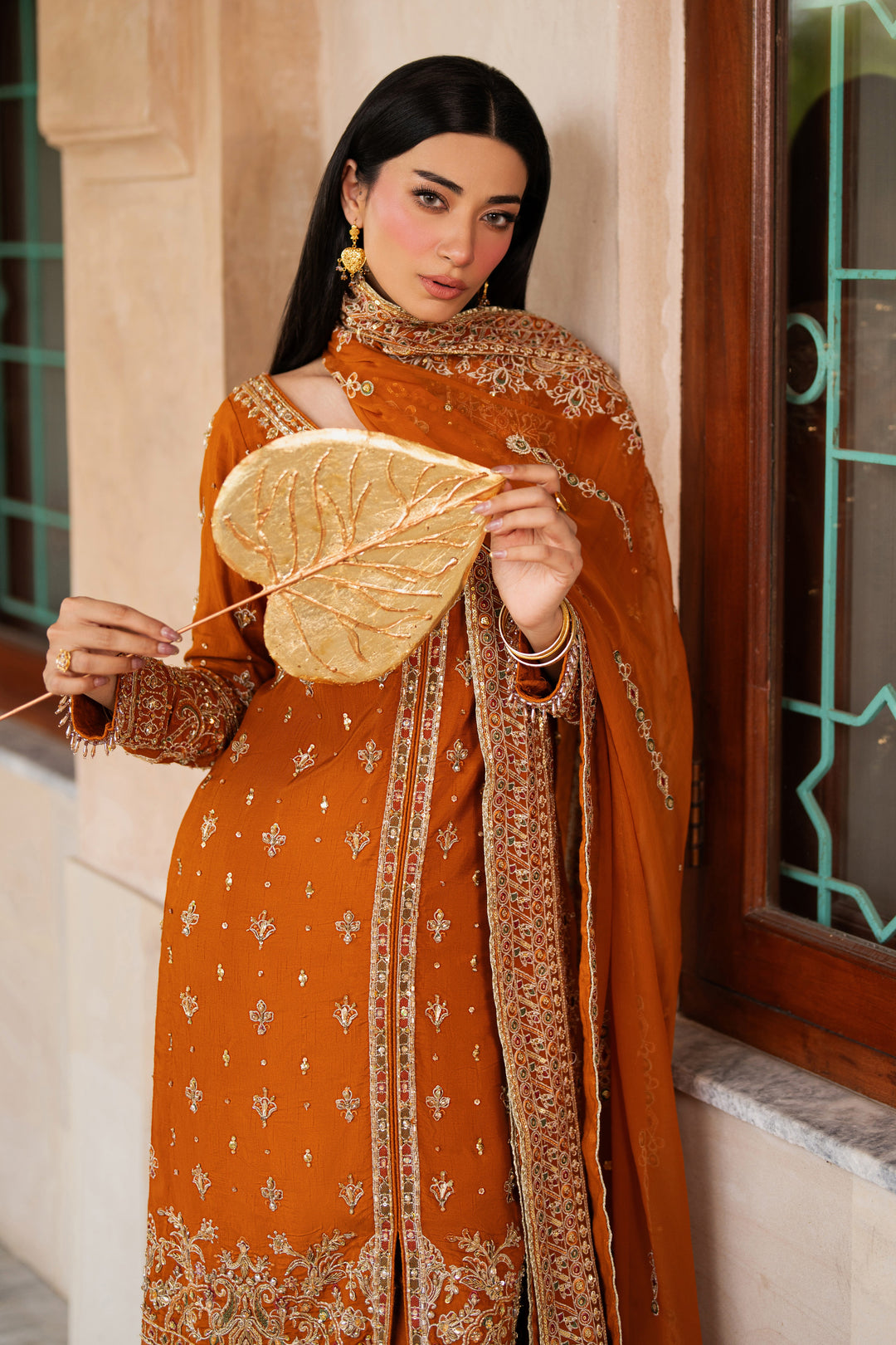 Front view of NAQSHI Gul-e-Farosh rust raw silk gown with adda work, sequin spray embroidery, rounded neckline, and soft chiffon dupatta styled for formal wear.
