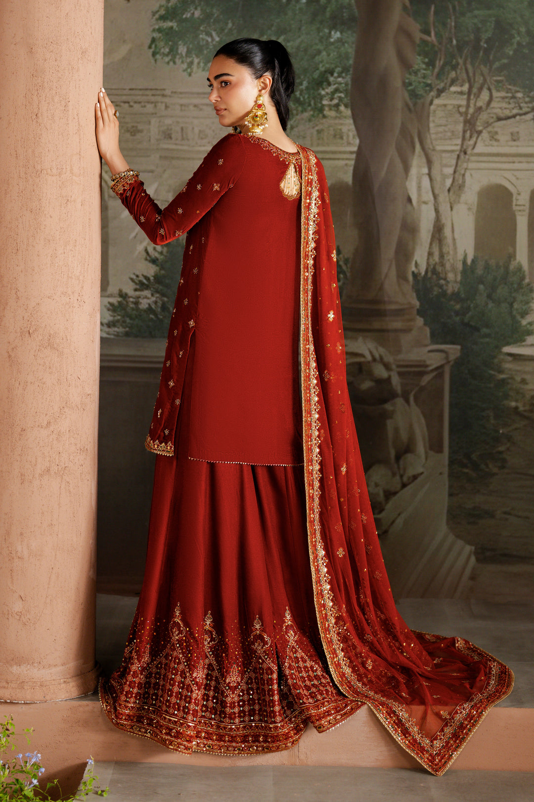 Side view of NAQSHI Vaneeza rust velvet sharara outfit showing full silhouette, detailed embroidery on shirt and flowing dupatta — ready-to-wear formal dress