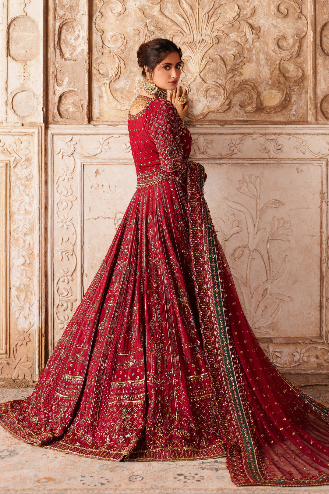 Side view of NAQSHI Gul Kand bridal lehenga in deep red with rich embroidery and long train for formal wedding occasions.