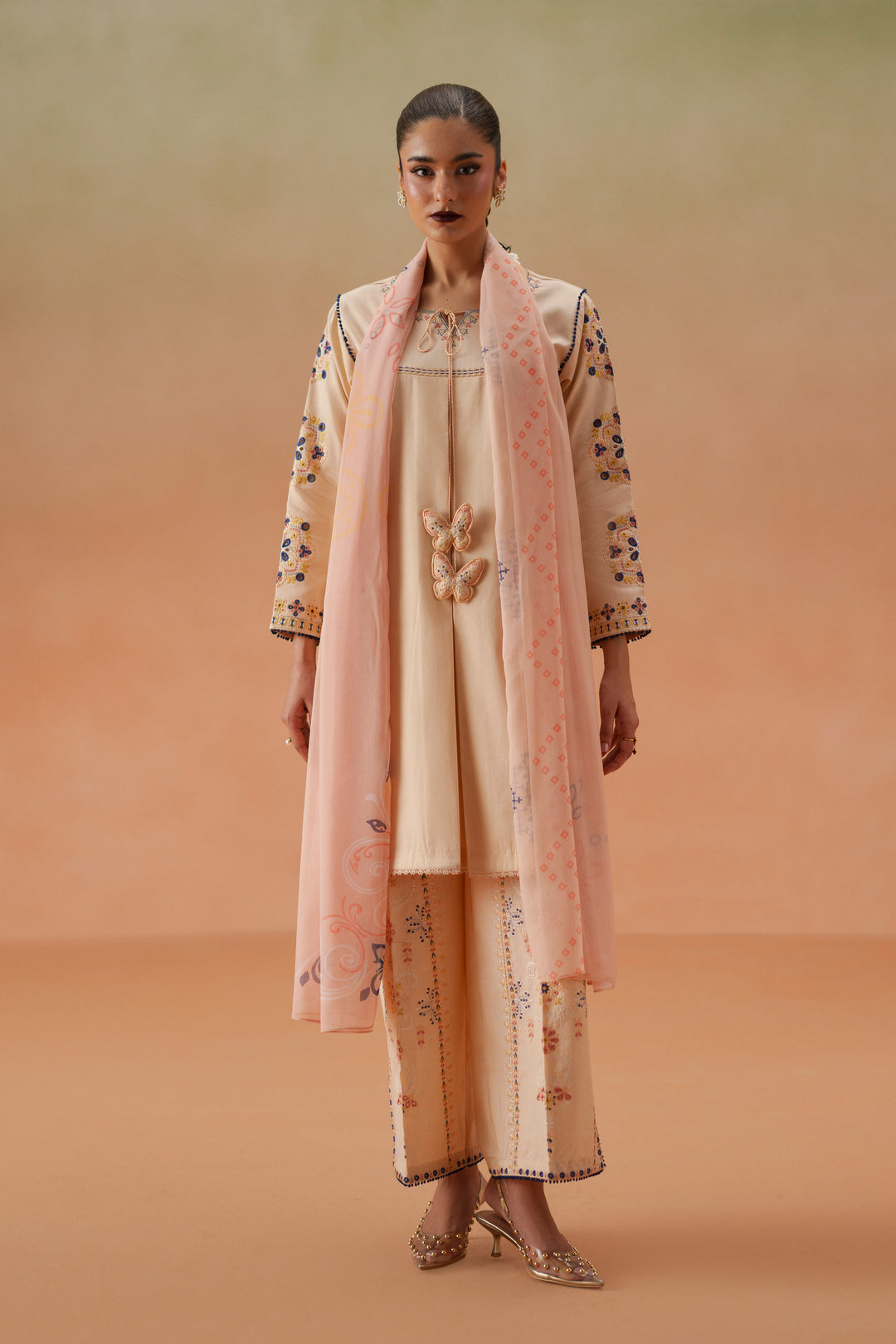 Model wearing Faye light peach embroidered lawn outfit with printed chiffon dupatta and cambric culotte trouser for festive daytime wear.