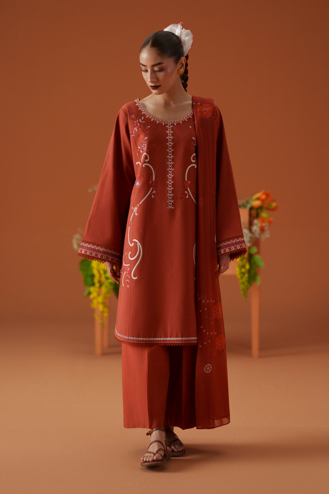 Model wearing Ophelia rust embroidered lawn outfit with cambric culotte trouser and printed chiffon dupatta for casual festive wear.