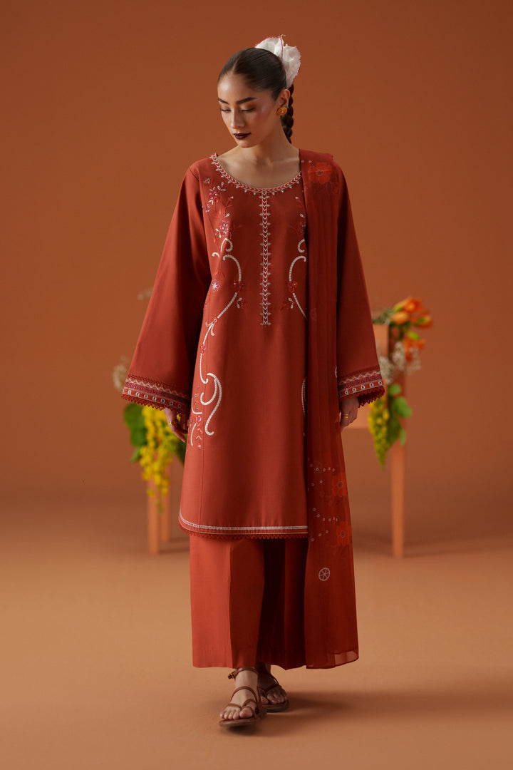 Model wearing Ophelia rust embroidered lawn outfit with cambric culotte trouser and printed chiffon dupatta for casual festive wear.