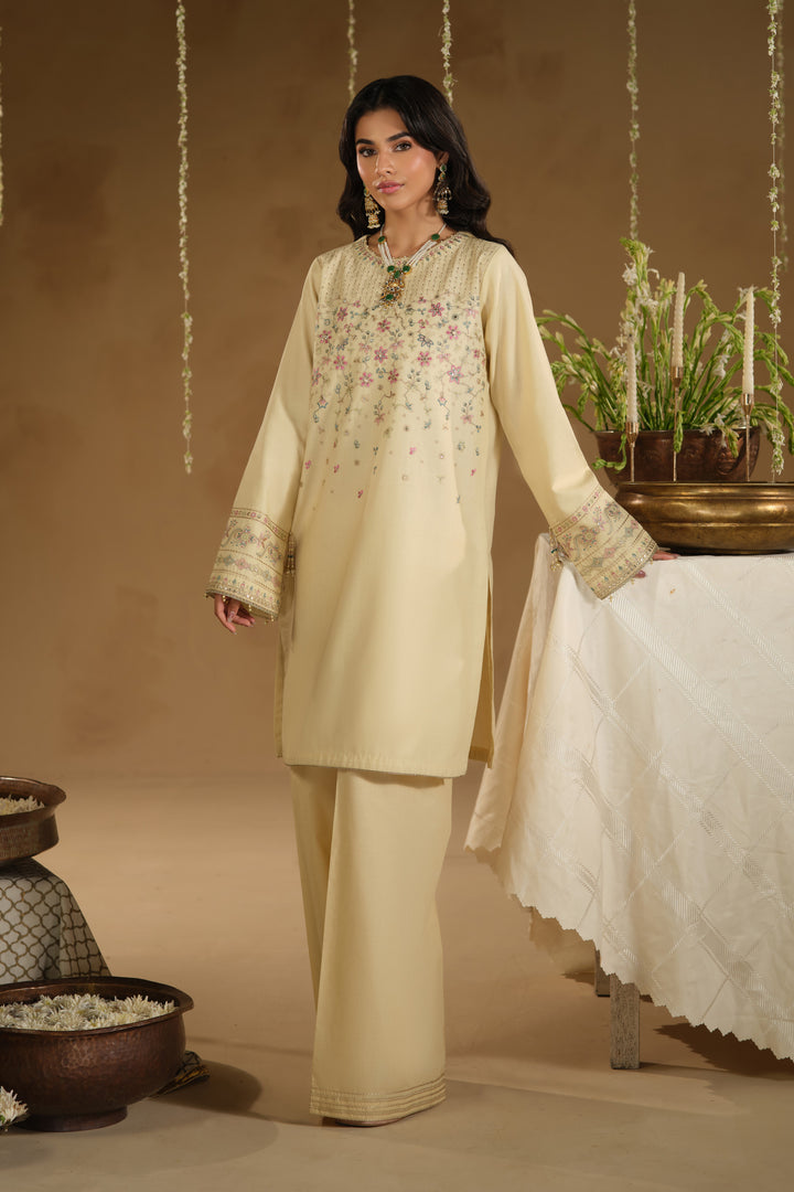 Full length side view of Arosel beige festive dress showing straight long shirt and wide culotte trousers