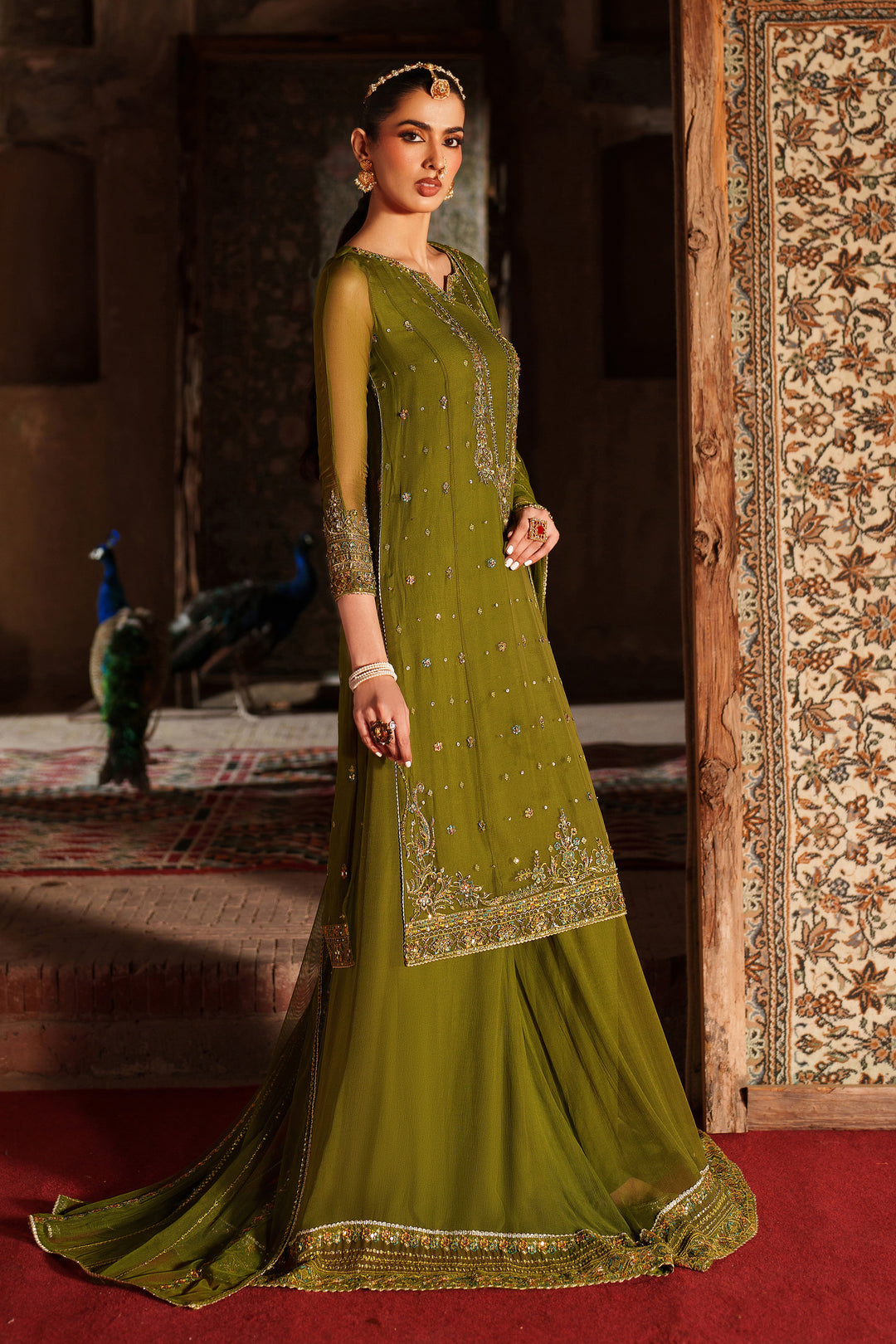 Woman in a green traditional outfit standing in a decorated room.