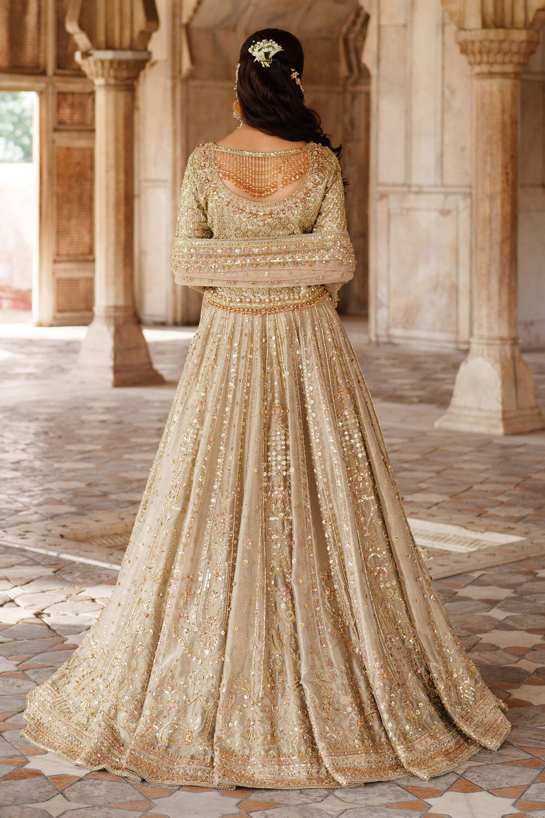 Back view of NAQSHI Ruhab champagne gold formal gown with heavy embroidery and full length flared design for special occasion dress.