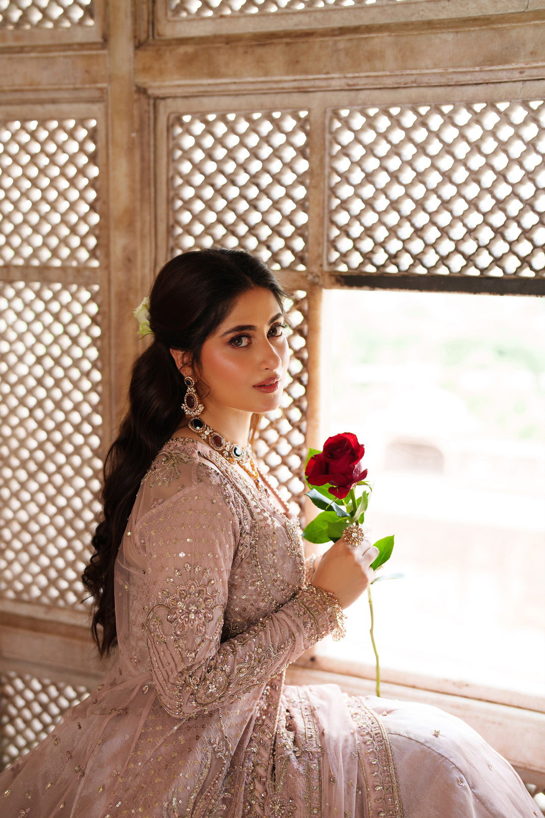 Portrait of NAQSHI Mareeha soft pink formal gown worn with elegant jewelry showing fine embroidered detail for wedding celebrations.