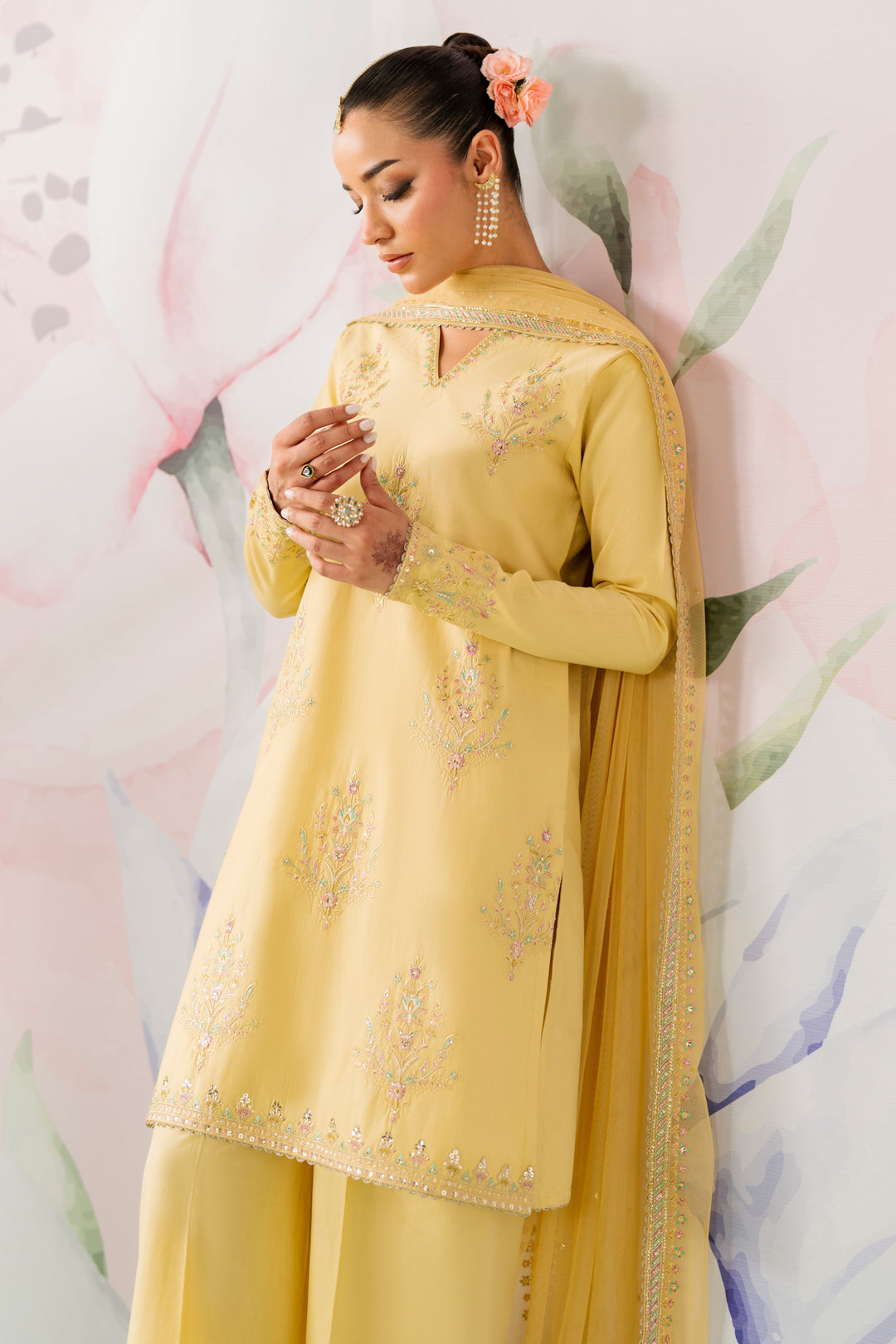 Side pose showing pariya  yellow long embroidered shirt with net dupatta and neat culotte trousers semi formal dress