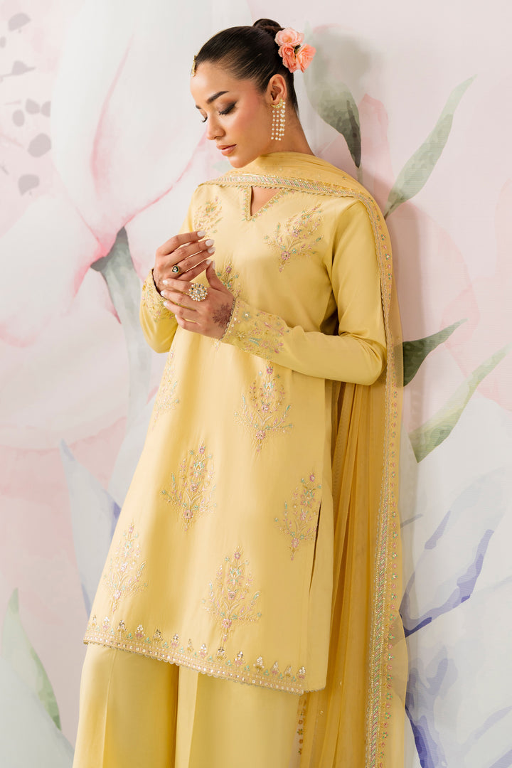 Side pose showing pariya  yellow long embroidered shirt with net dupatta and neat culotte trousers semi formal dress