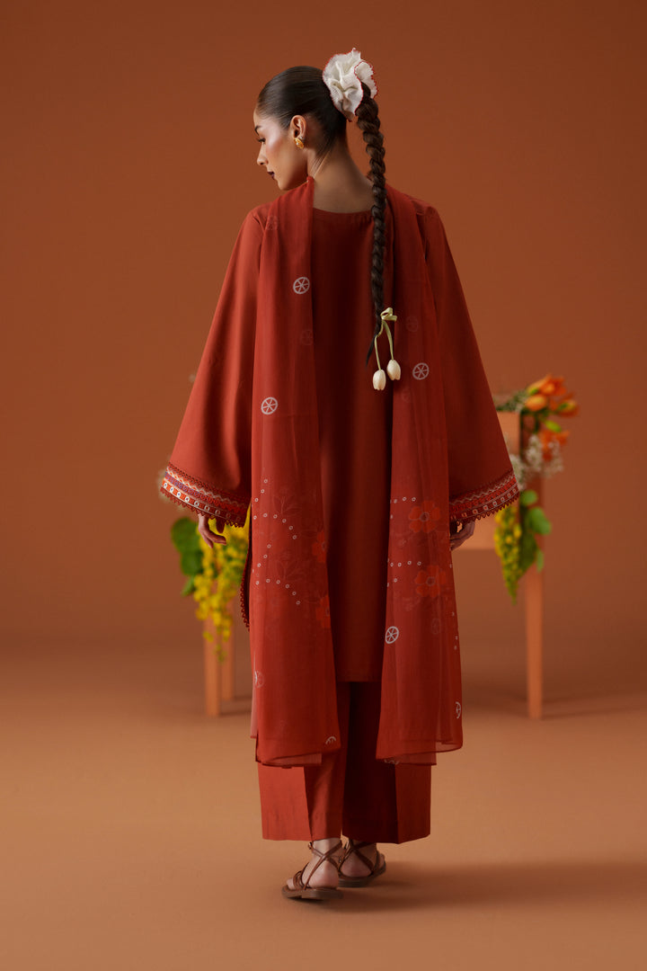 Back view of Ophelia rust 3-piece outfit with long embroidered lawn shirt, printed crinkle chiffon dupatta, and relaxed trouser.