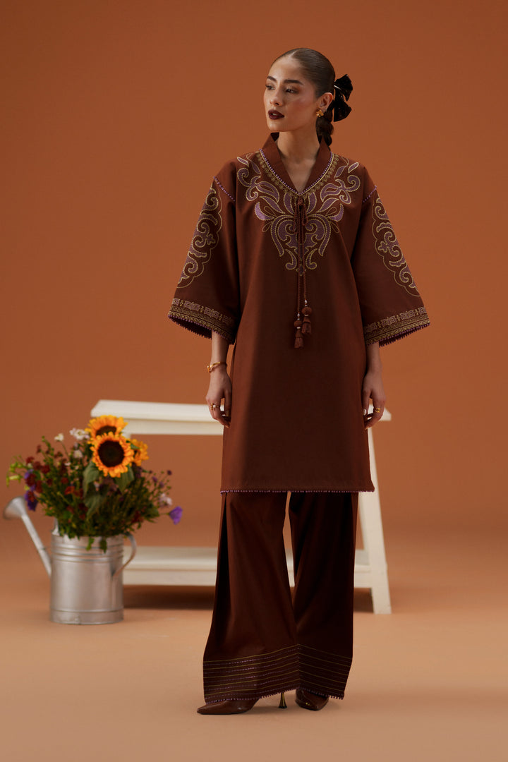 Model wearing Fiona brown casual pret outfit with embroidered neckline, loose lawn shirt, printed dupatta, and cambric shalwar.