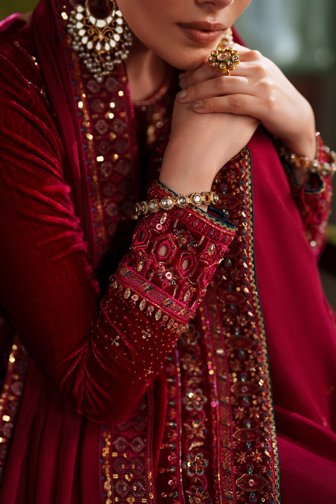 Close-up detail of NAQSHI deep red formal dress showing embroidery on neckline and sleeves