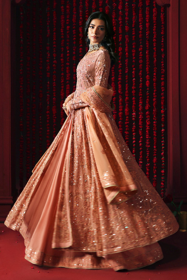 Model wearing NAQSHI Ashiayana peach 3-piece set: frock with embroidery, matching trousers and net dupatta