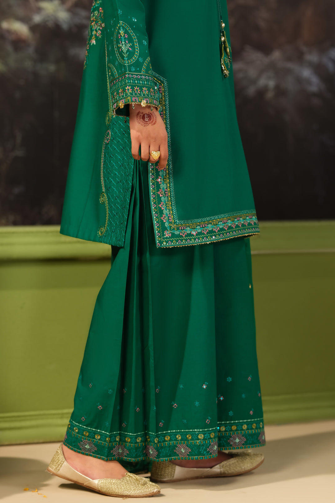 Detail view of NAQSHI Malika green embroidered culotte trousers and shirt hem with decorative border