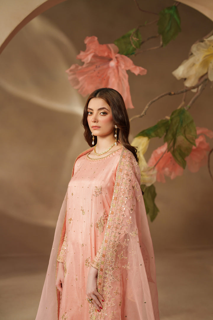 Model wearing NAQSHI Jinan peach pink luxury pret dress with embroidered details and light dupatta, giving a graceful event-ready look.