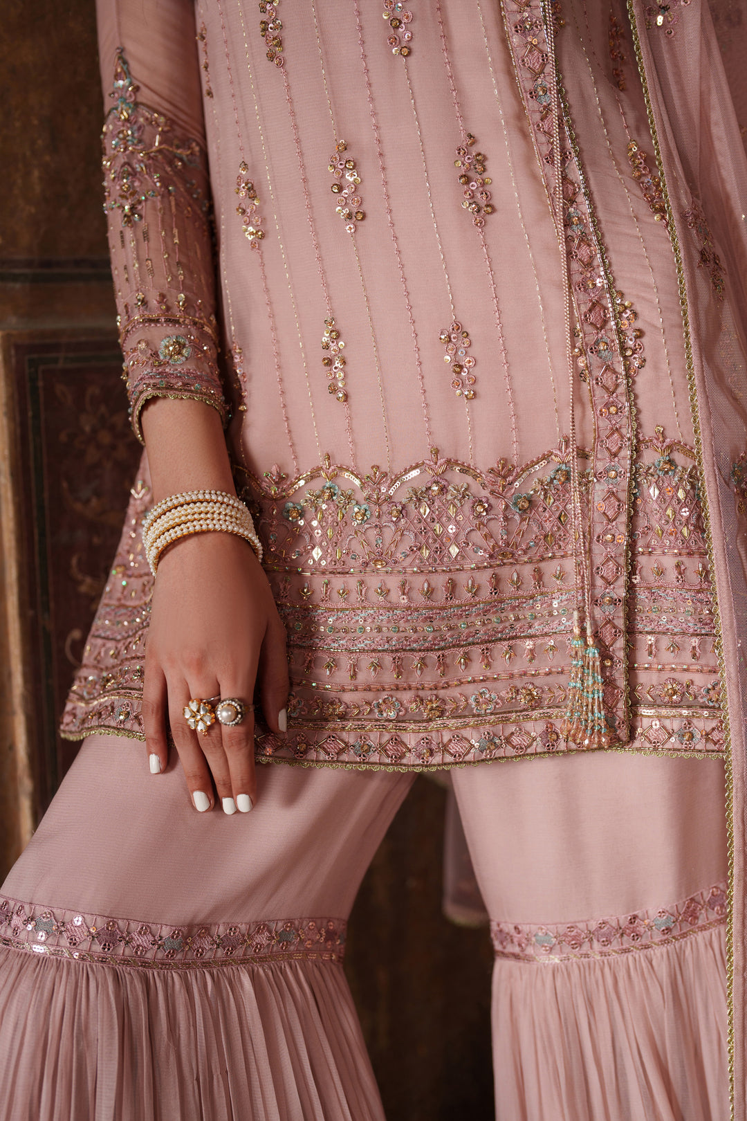 Close-up of a pink embroidered traditional outfit with intricate designs.