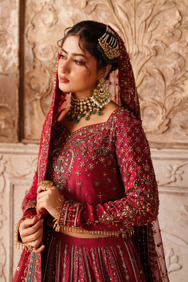 Portrait close up of NAQSHI Gul Kand bridal lehenga showing detailed embroidery and ornamental accessories on red formal dress.