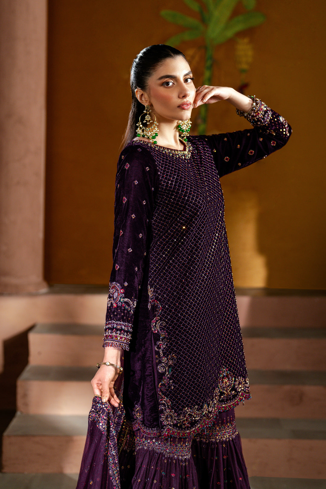 Woman wearing a dark purple embroidered outfit with a blurred background