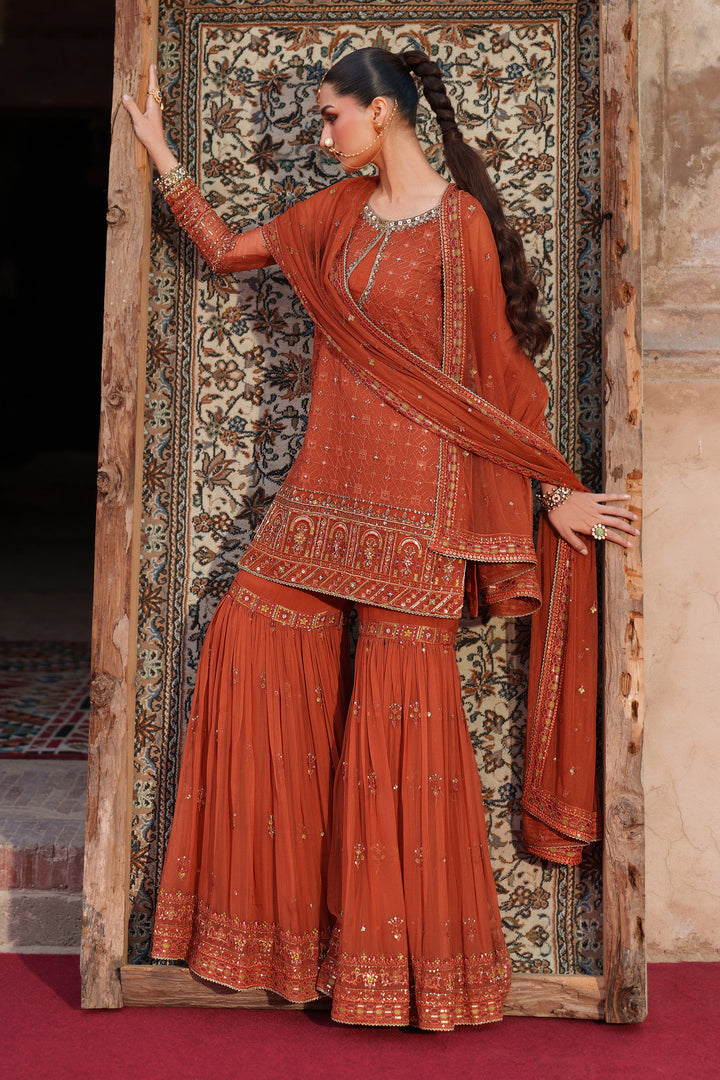 Woman in traditional red outfit standing in front of an ornate door.
