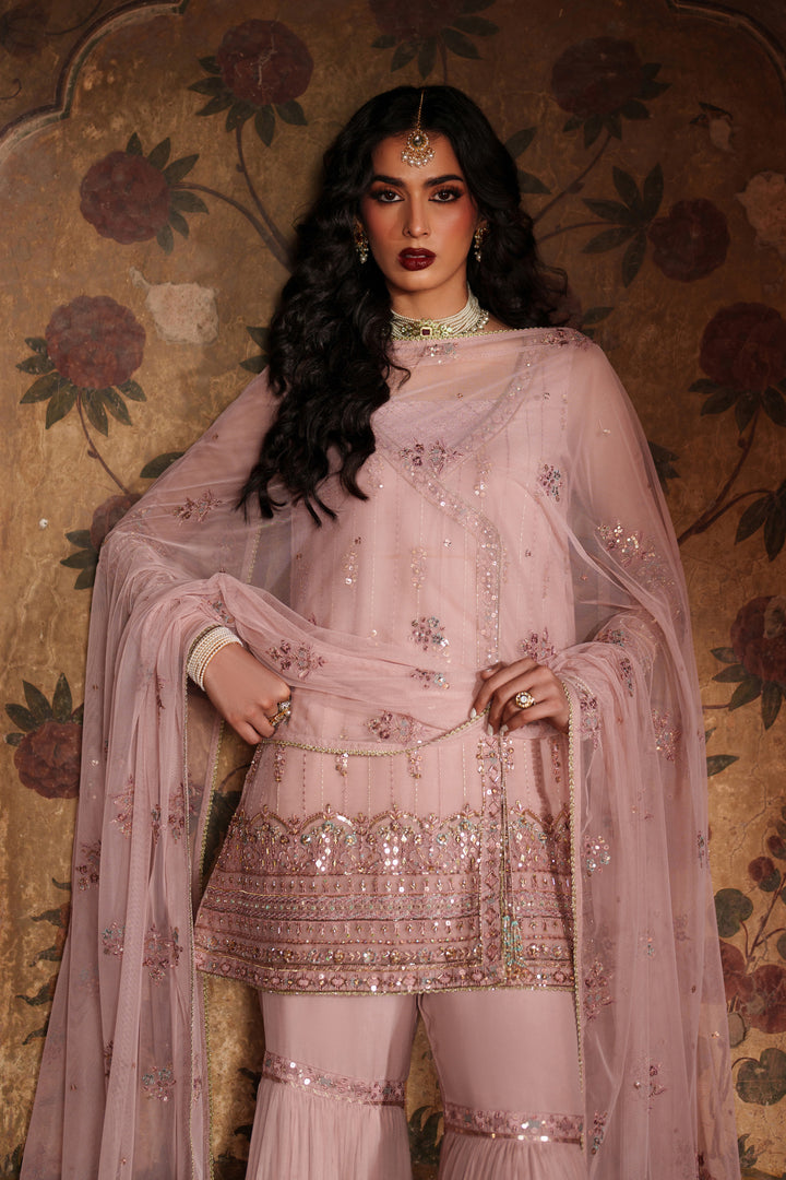 Woman in a pink embroidered traditional outfit with a floral background