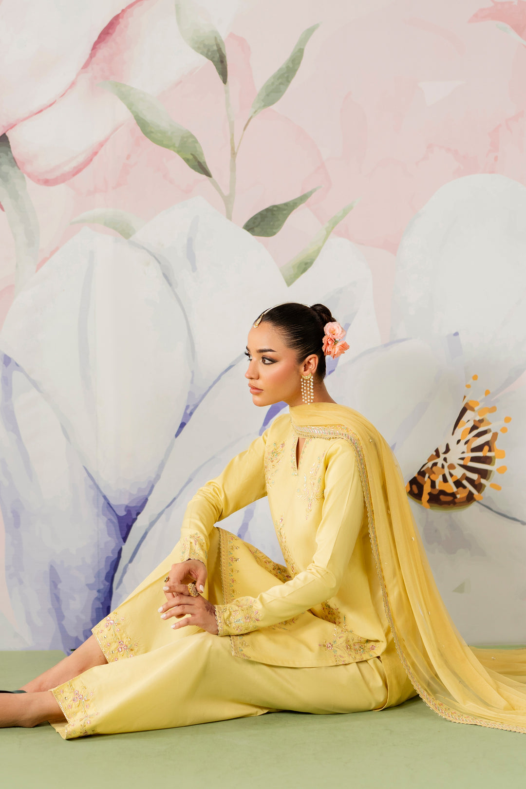 Sitting pose of pariya yellow ready to wear 3 piece suit with flowing net dupatta suitable for Eid and family functions