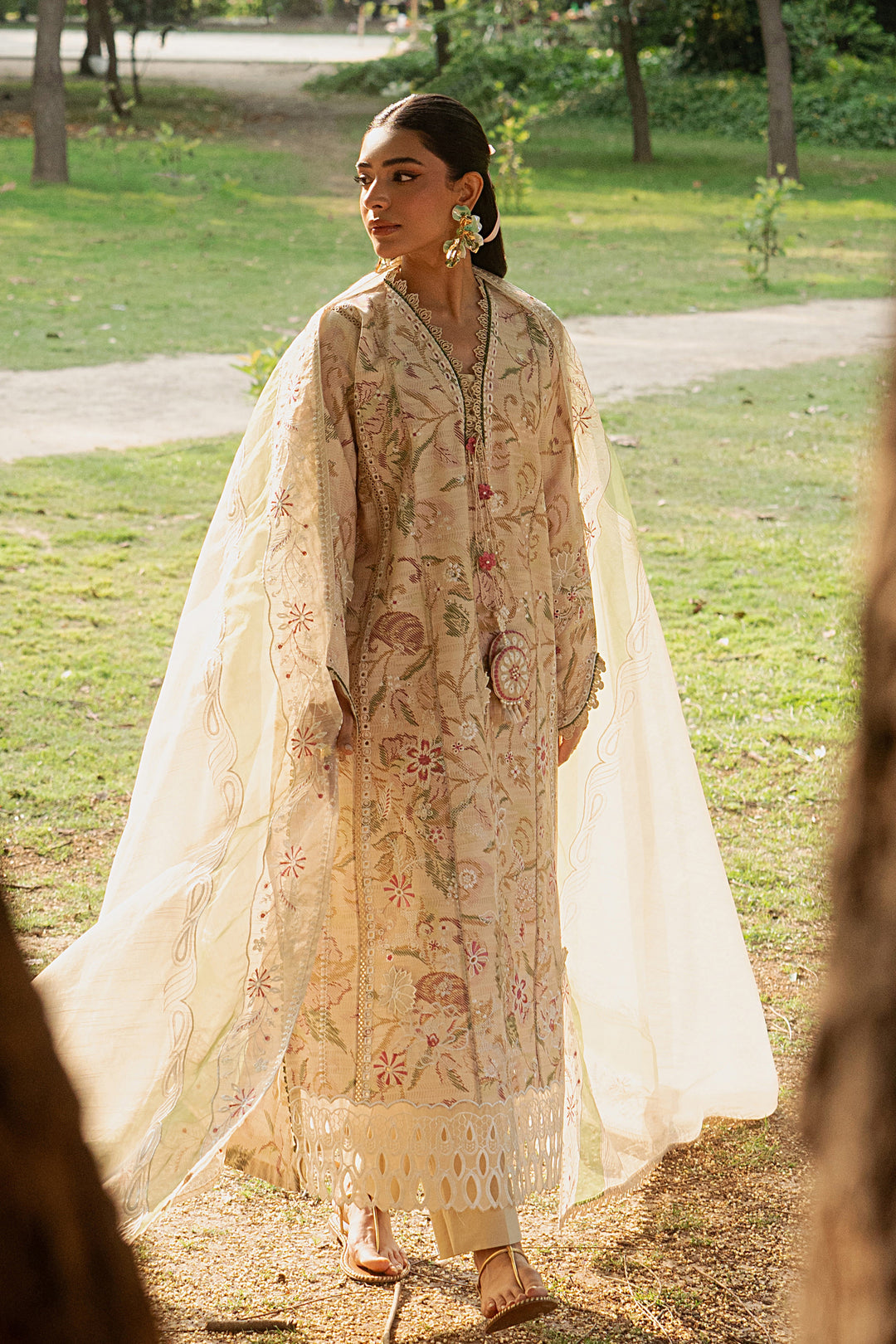 Side angle of Andalib skin lawn dress highlighting fitted sleeves, floral embroidery, tassel detail and lace finishing