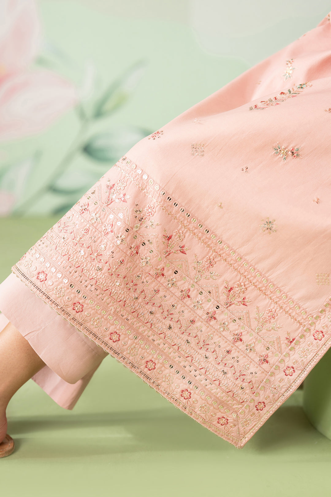 Close-up of a pink embroidered fabric on a green background
