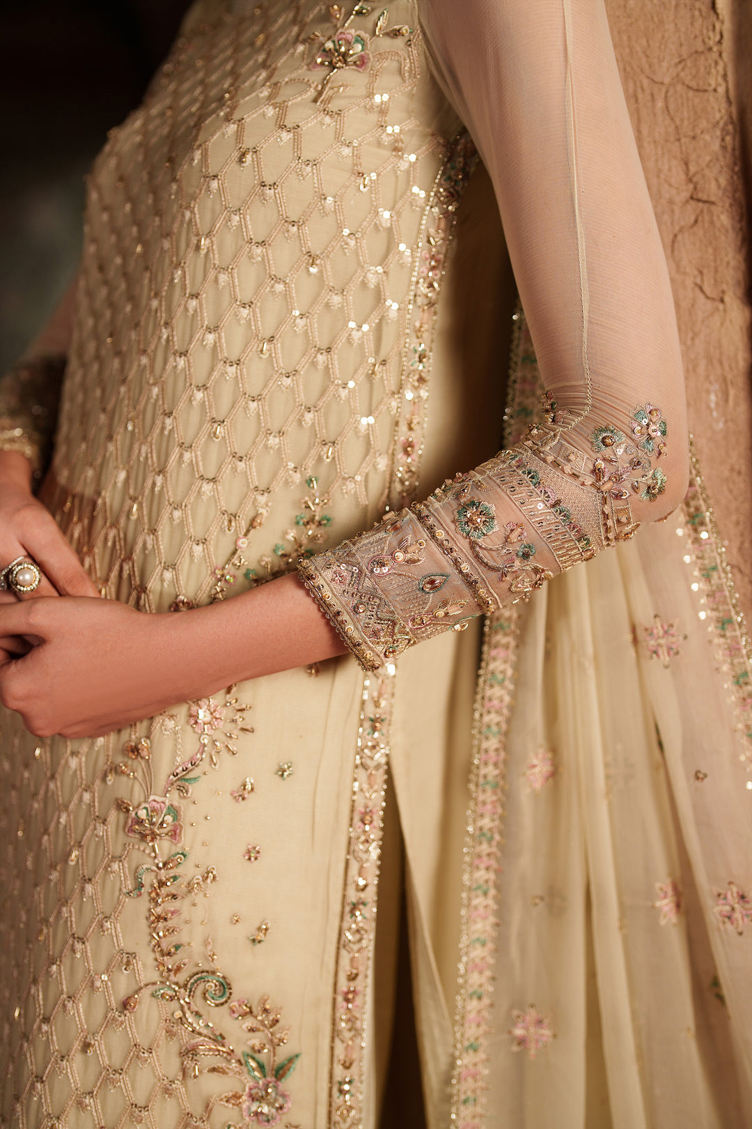 Close-up of a person wearing a beige embroidered outfit with intricate designs.