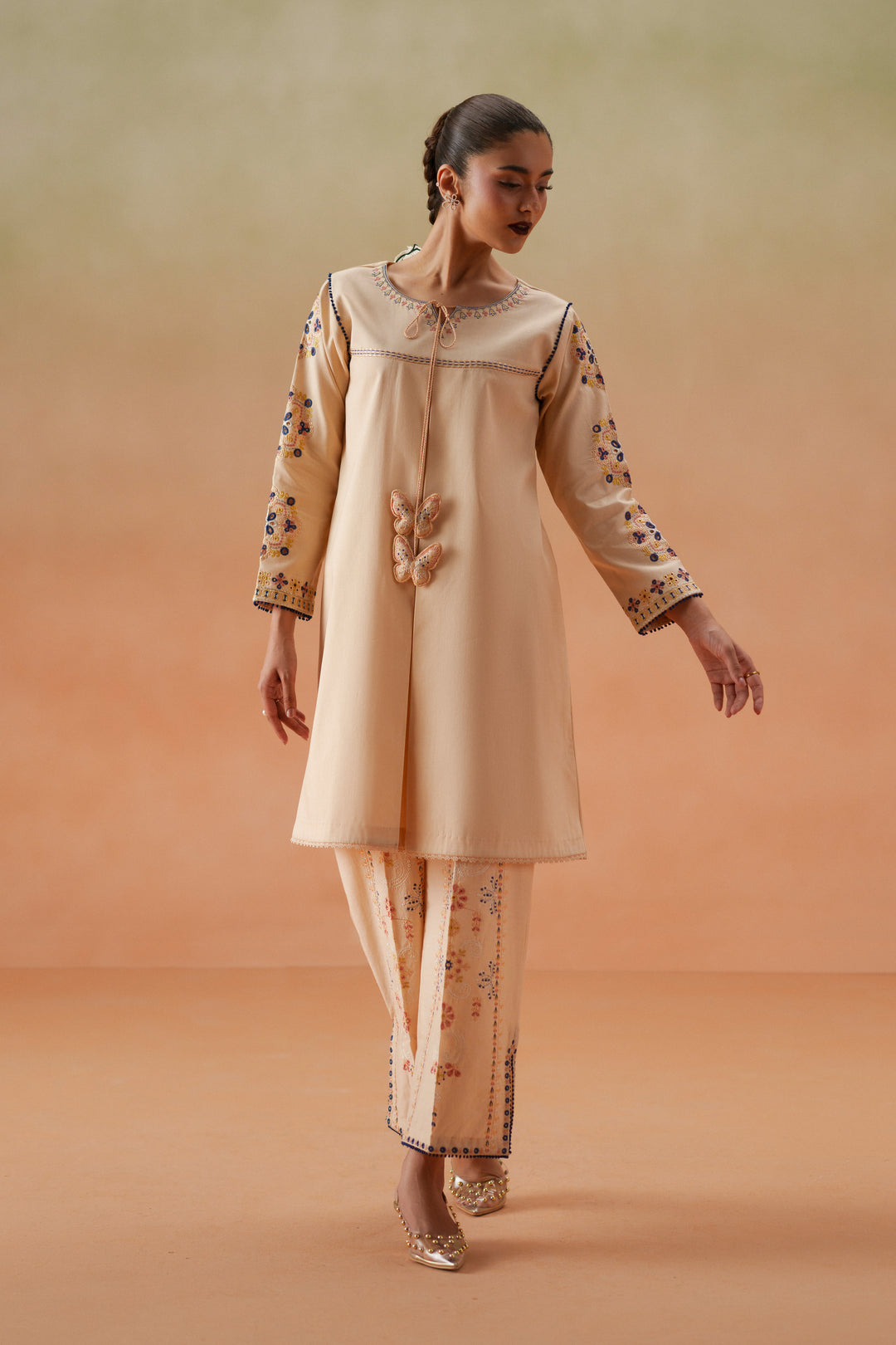 Front walking pose of Faye light peach casual pret outfit with embroidered lawn shirt, culotte trouser, and printed chiffon dupatta.