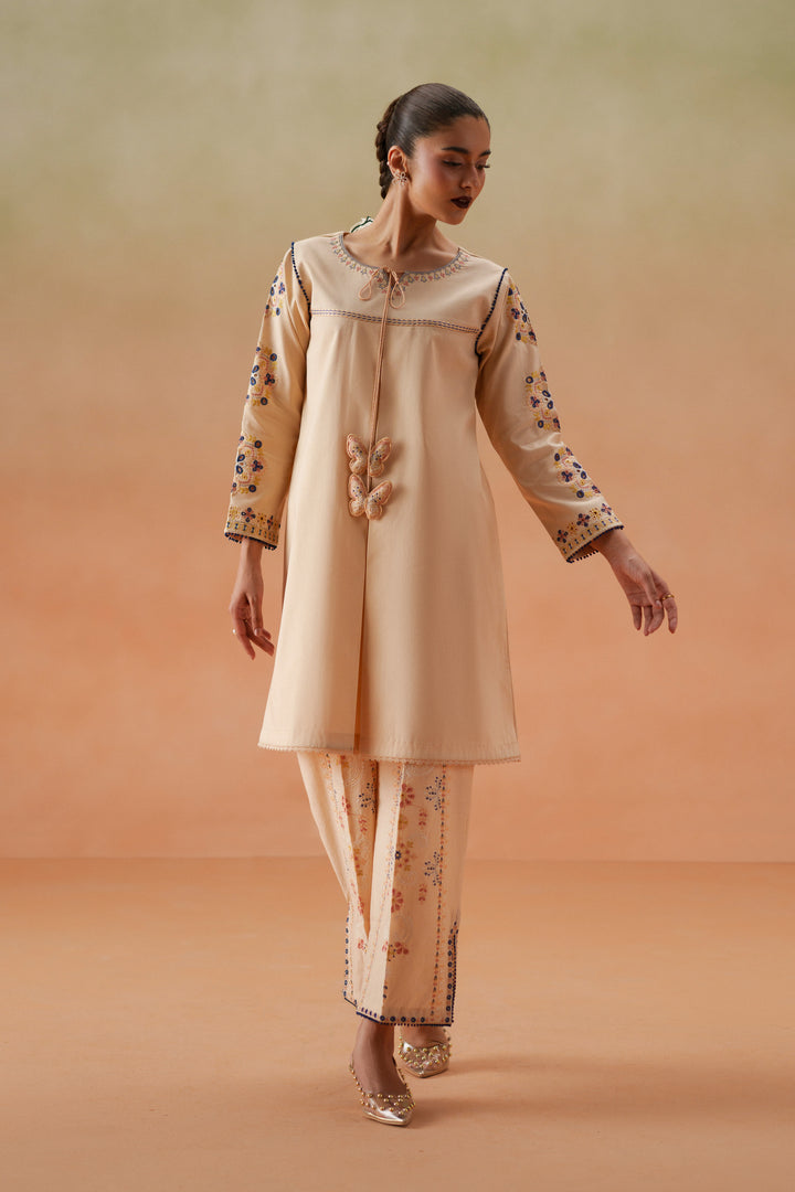 Front walking pose of Faye light peach casual pret outfit with embroidered lawn shirt, culotte trouser, and printed chiffon dupatta.