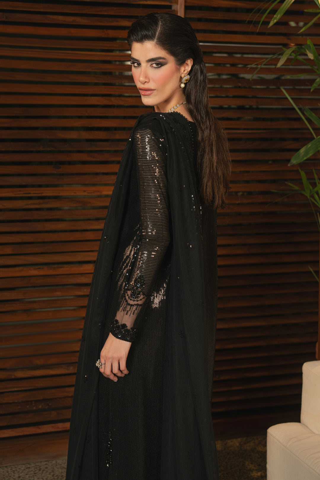 Side view of NAQSHI Horleyn black formal outfit highlighting short slit, hanging details, fitted sleeves, and smooth straight trouser fit.