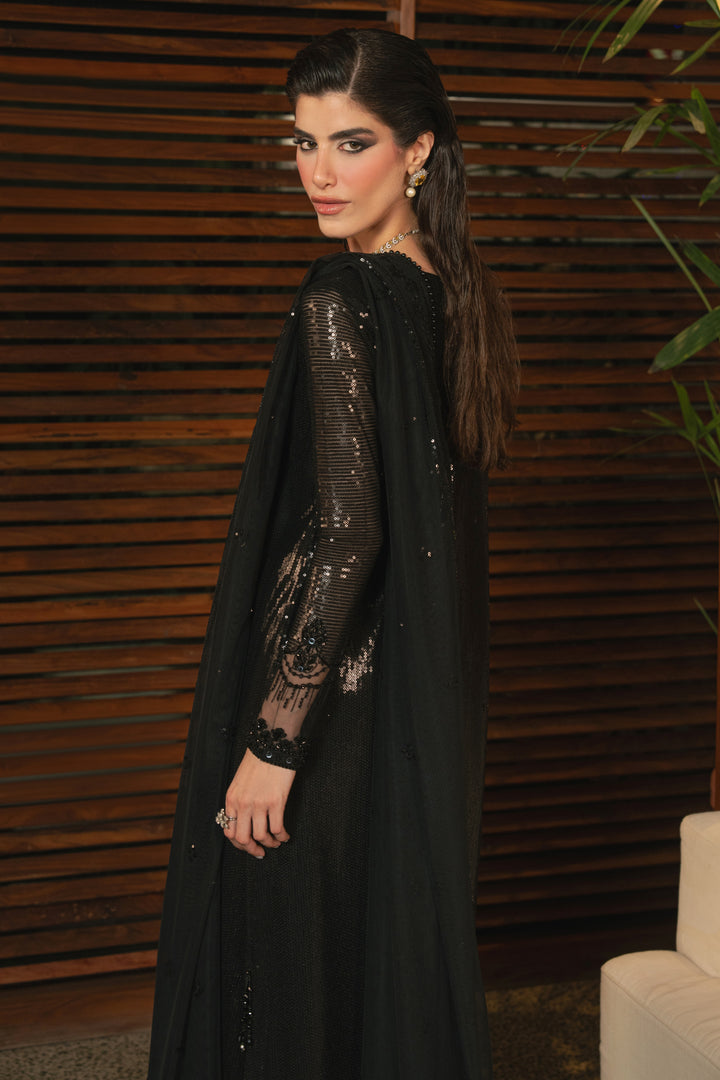 Side view of NAQSHI Horleyn black formal outfit highlighting short slit, hanging details, fitted sleeves, and smooth straight trouser fit.