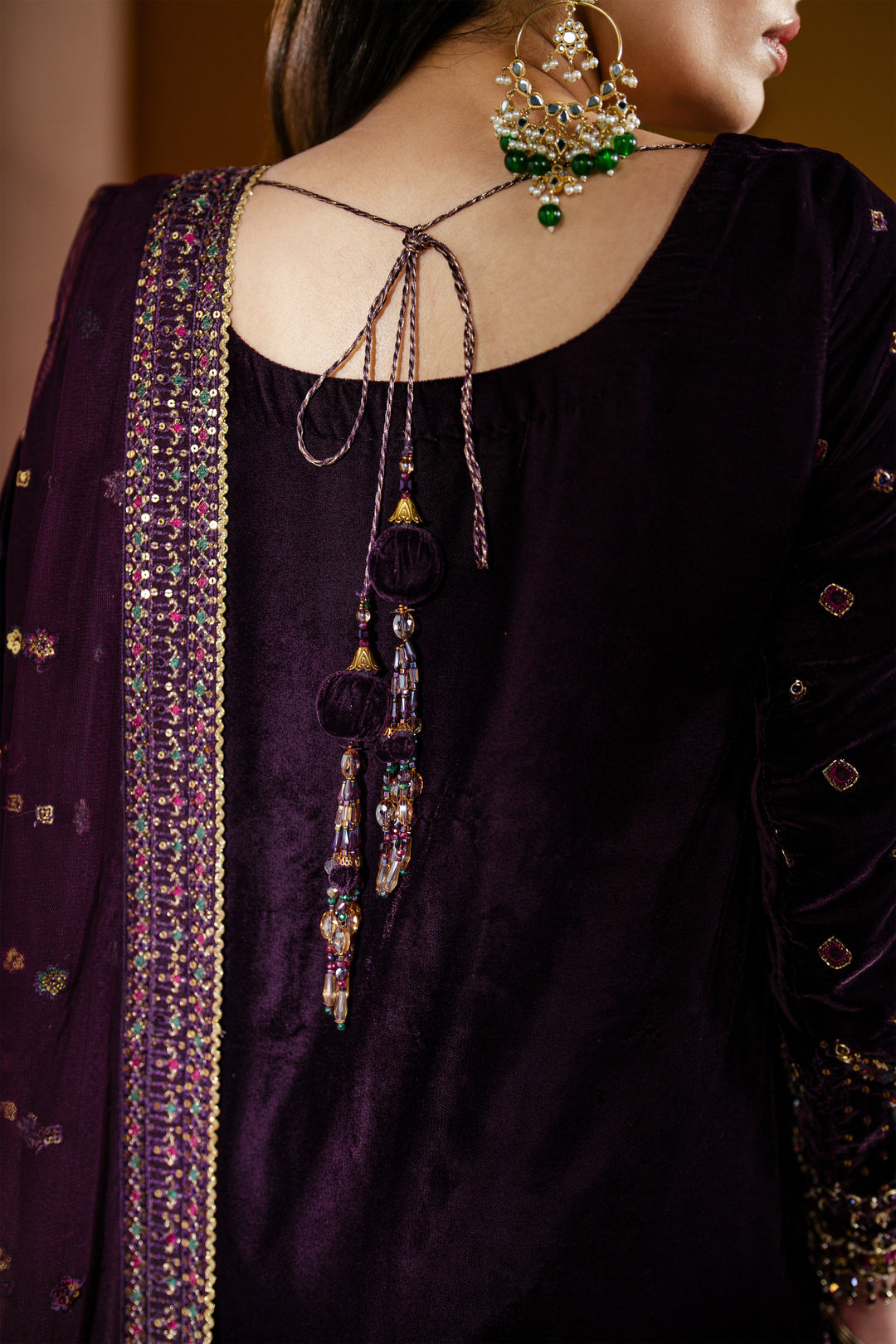 Close-up of a person wearing a dark purple traditional outfit with intricate detailing.

