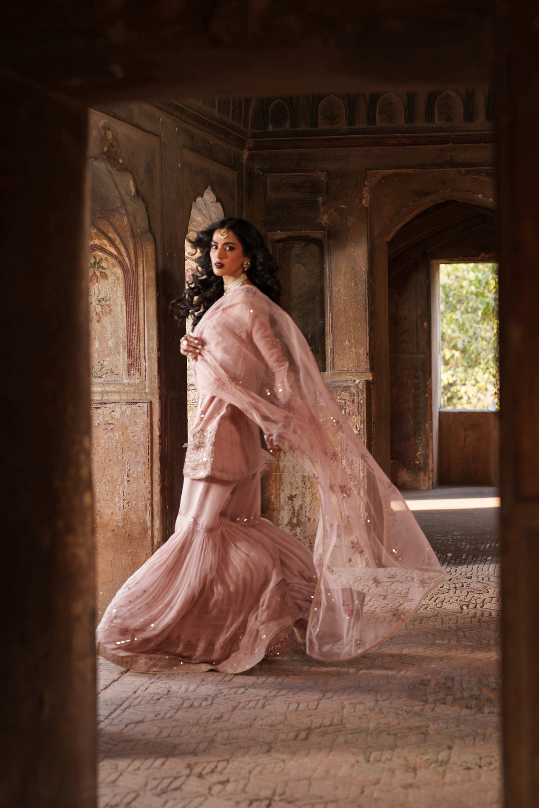 Woman in a pink traditional outfit standing in an ornate architectural setting
